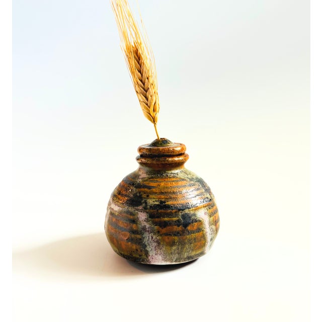 A vintage studio pottery bud vase. Finished in natural colored drip glazes. Unique design with a detachable lid that has a...