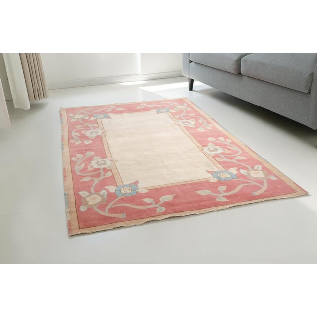 This is a vintage Turkish Oushak rug from the Mid 20th Century. The piece was hand-knotted.