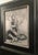 This artwork features a figure seated on the ground, holding a stick, surrounded by a textured landscape of trees and...