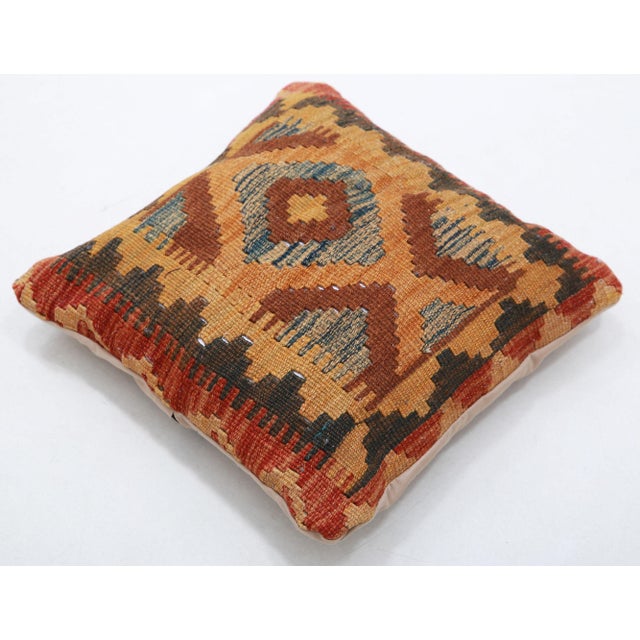 A one-of-a-kind handwoven Afghan wool kilim accent pillow featuring concentric ikat diamond in warm tones. Cut and sewn by...