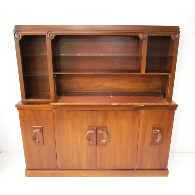 A very well crafted two- piece bar cabinet in a medium dark walnut tone having a pull- down door with copper surface for...