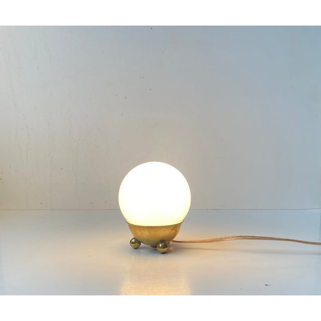 Unusually small yet stylish table lamp composed of a stylized tripod brass base with ball feet and a free-resting mat...