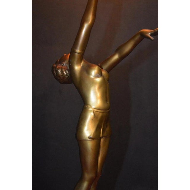 A striking french art deco figural table lamp dating to the 1930s, combining sculptural metalwork with marble, black glass...