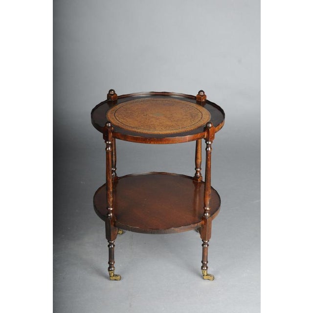 Beautiful round side table, England, 20th century The table features two round tiers; the top is embossed with leather and...