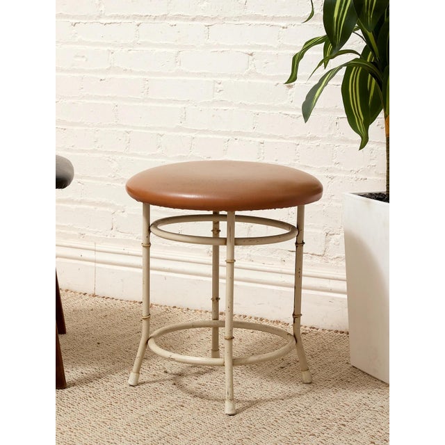 A charming vintage stool with a slender white metal frame designed to mimic the segmented look of bamboo. The rounded...