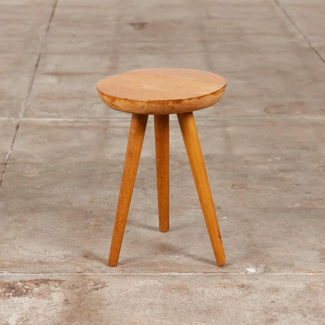 Patinated wooden tripod milking stool. The stool features a thick hand carved rounded seat with visible growth rings, that...
