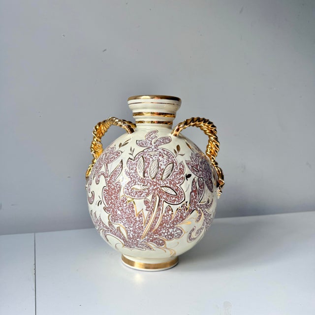 Vintage 1960s Italian regency gold tassel pottery vase. The piece is ornate with twisted tassel handles on either side in...