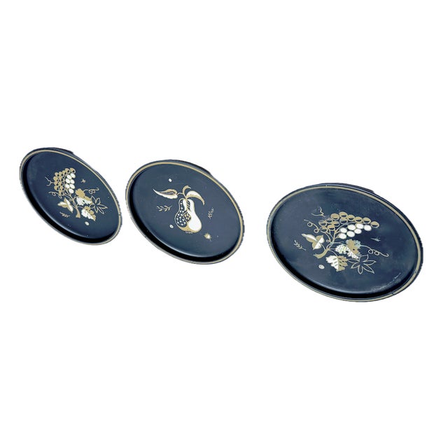 Vintage set of three Midcentury stylized and hand-painted fruit tole trays. Two trays depict stylized grapes and one tray...