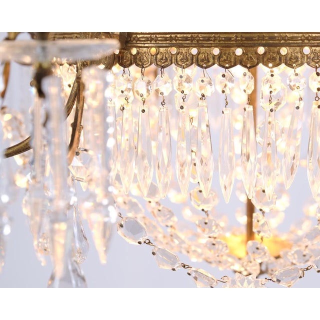 French antique crystal chandelier from the 1880s with decorative bronze detailing and numerous prisms. The chandelier has...