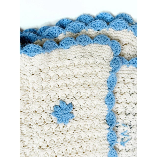 This charming vintage handmade crochet blanket features a textured white base accented with raised 3D blue flowers across...