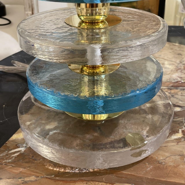 Pair of table lamps with a structure formed by solid Murano glass discs in light blue and transparent shades. These are...