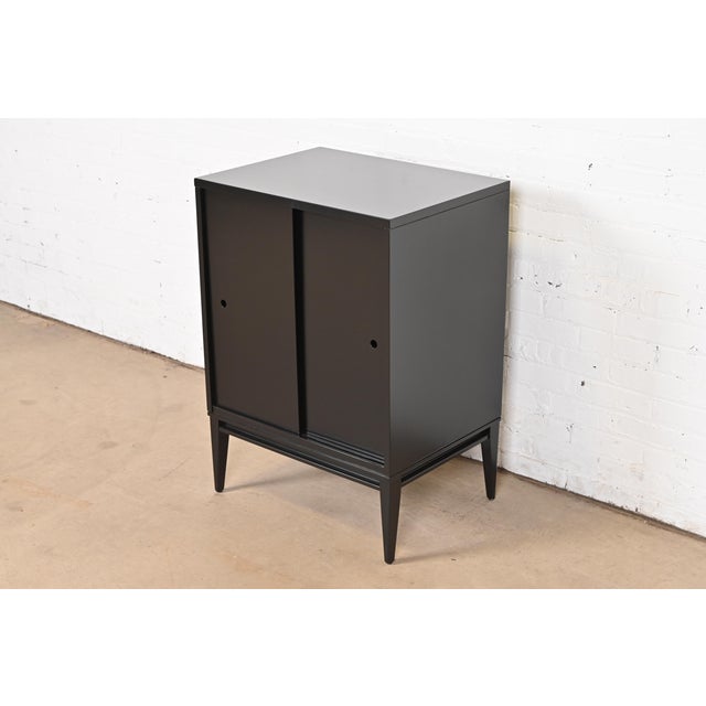 A gorgeous Mid-Century Modern black lacquered solid maple record cabinet or bar cabinet with sliding doors By Paul McCobb...