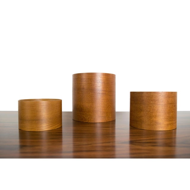 A set of three cylindrical Japanese teak nesting containers. Bentwood construction. Made in Japan. Sticker affixed to...