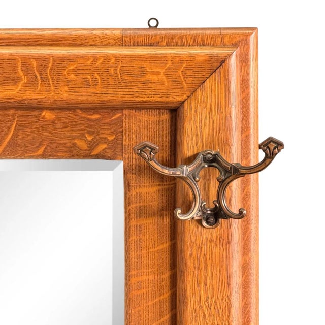 A circa 1910 hall mirror of quarter-sawn oak having four copper-plated brackets mounted to the face; each with four hooks...