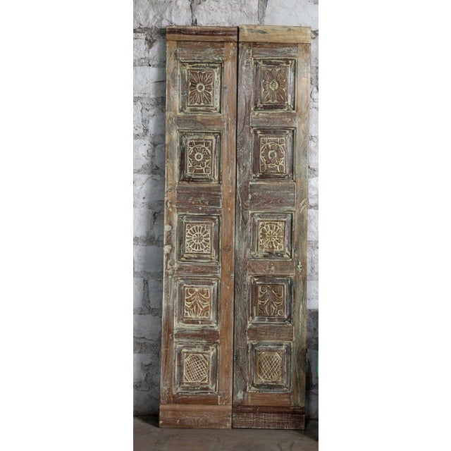 A stunning set of antique double doors showcasing intricate floral hand carvings and a richly aged rustic patina. Crafted...