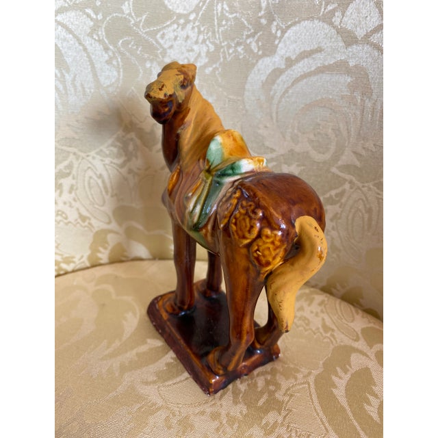 Tang Style Horse in a Smaller Size and in Earth Tone Colors with a Splash of Green on the Saddle . I am unable to make out...