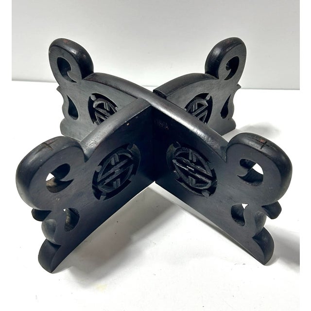 A vintage Chinese carved wood display stand formed from two interlocking pierced panels with curved supports and circular...
