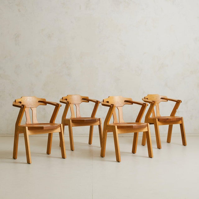A 1960s French dining set composed of an octagonal dining table and a matching set of four carved oak chairs. Unified by...