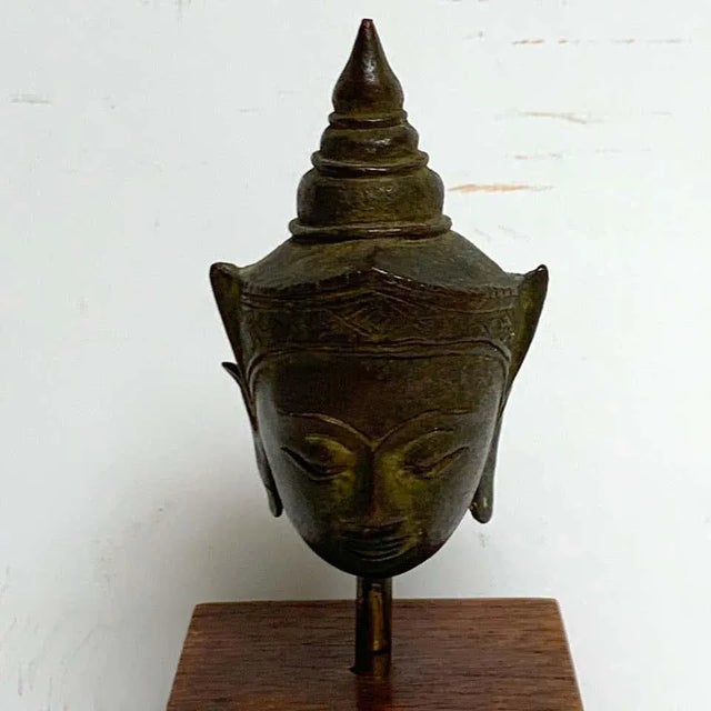Miniature Bronze Thai Buddha Head, Museum mounted on a stepped wood pedestal. 20th century or older. The sculpture alone...