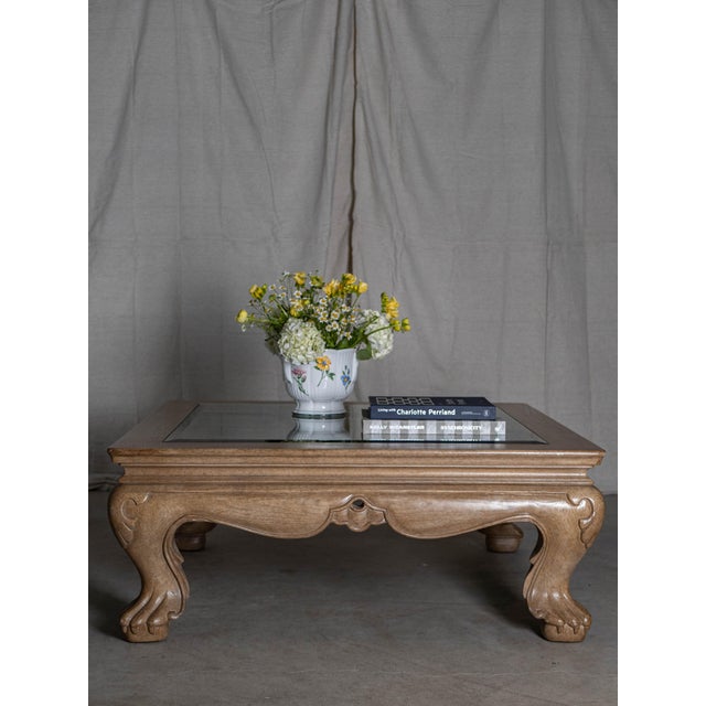 Elegant and richly detailed, this vintage Marge Carson coffee table features intricately carved wood legs and a beveled...
