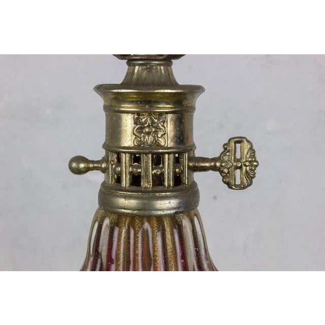 Rich ruby red Murano glass infused with shimmering gold inclusions gives this Italian Mid-Century table lamp its...