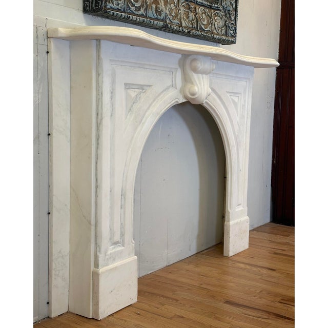 Early 20th century Neoclassical style mantel in white marble. The scrolling keystone carving references Louis XVI styling,...