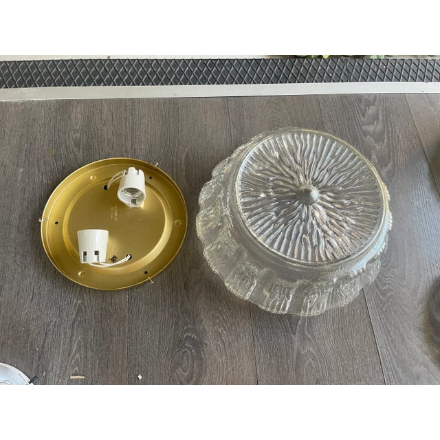 This flushmount features a clear, textured glass design that creates a visually striking and elegant appearance. The...