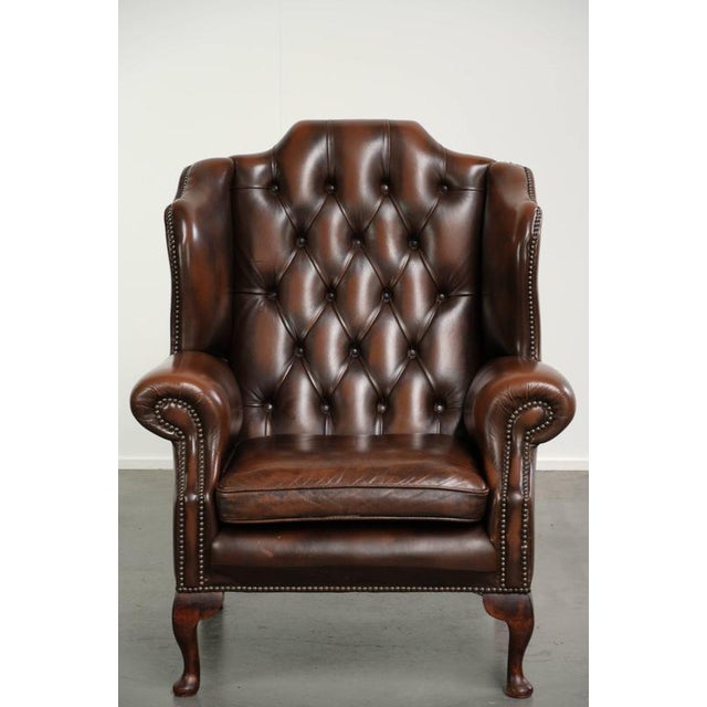 This elegant cowhide Chesterfield wing armchair is crafted in a beautiful dark brown color and is finished with decorative...