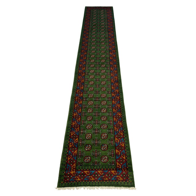 A long hallway runner with a rich green field, two rows of repeating geometric medallions, and smaller motifs between...