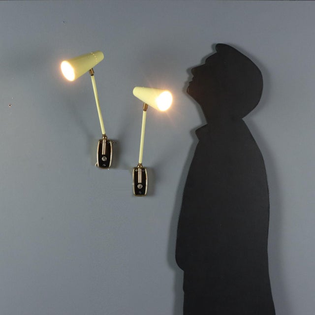 Two vintage Stilnovo wall lamps from the late 1950s, adjustable and made of yellow lacquered metal with brass joints. The...