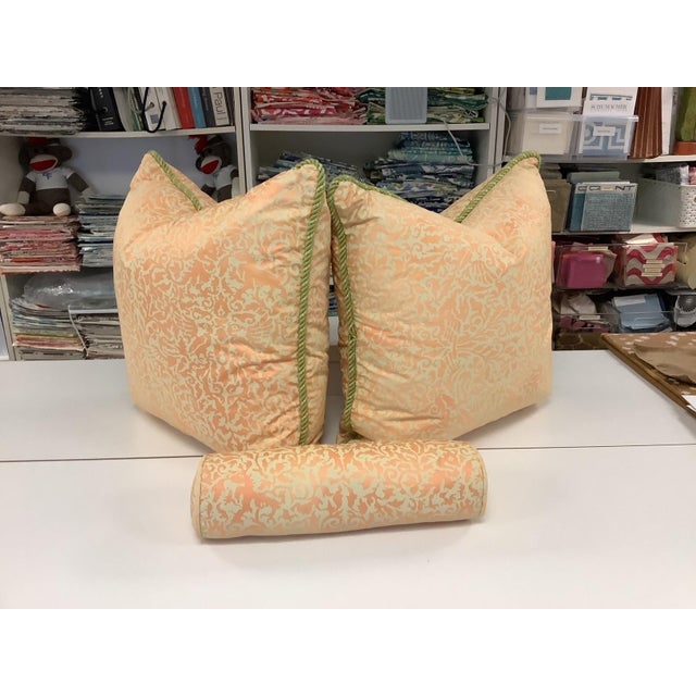 Two 21" square down filled pillows in peach and cream Fortuny-style fabric and one 14" X 4" down filled bolster in peach...