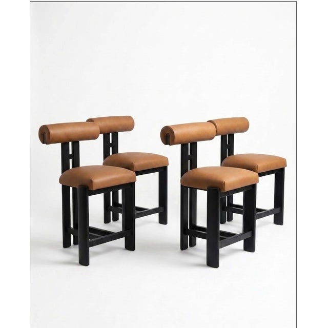 Set of 4 custom counter stools. Upholstered in high performance faux leather. Wood finish in Noir with blackened silver...