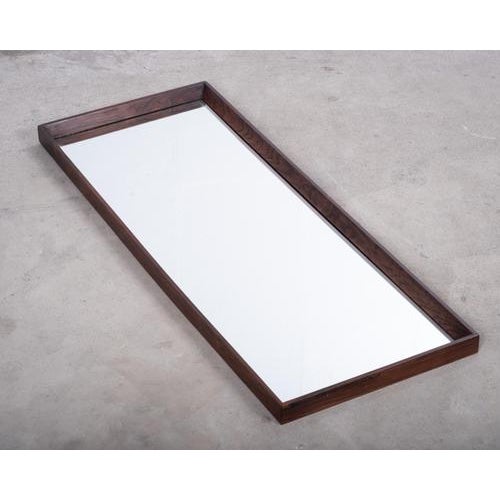 Elegant elongated wall mirror crafted in beautifully grained rosewood, produced in Denmark during the 1960s. A timeless...
