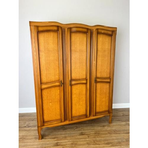 An elegant Vintage French Louis wardrobe in oak, featuring three beautifully shaped panelled doors, a gently curved top,...