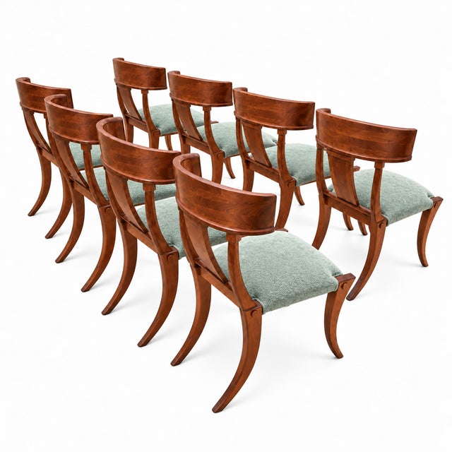 A striking set of 8 walnut Klismos dining chairs featuring beautifully figured wood grain, sweeping curved backrests, and...