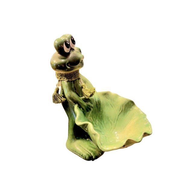 A sweet vintage frog holding a lily pad catchall trinket statue. The sweet little frog has such a cute happy face while...