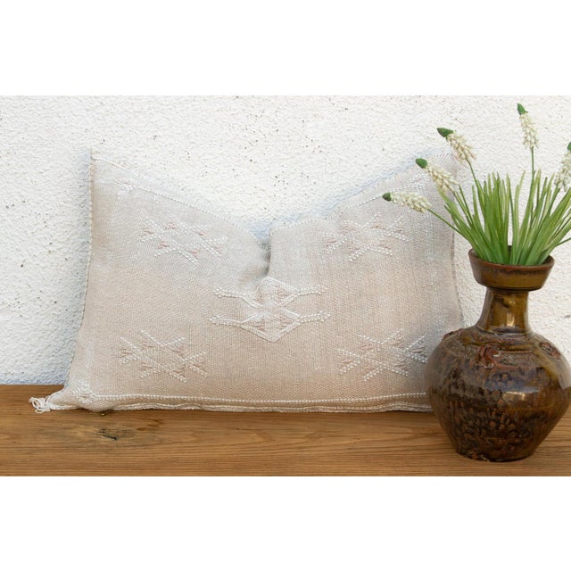 Two stacked diamond medallions rest side by side at the center of this handcrafted Moroccan cactus silk lumbar pillow,...
