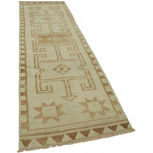 This exquisite runner rug is a rare example of tribal craftsmanship, hand-knotted by the women of the Herki tribe during...