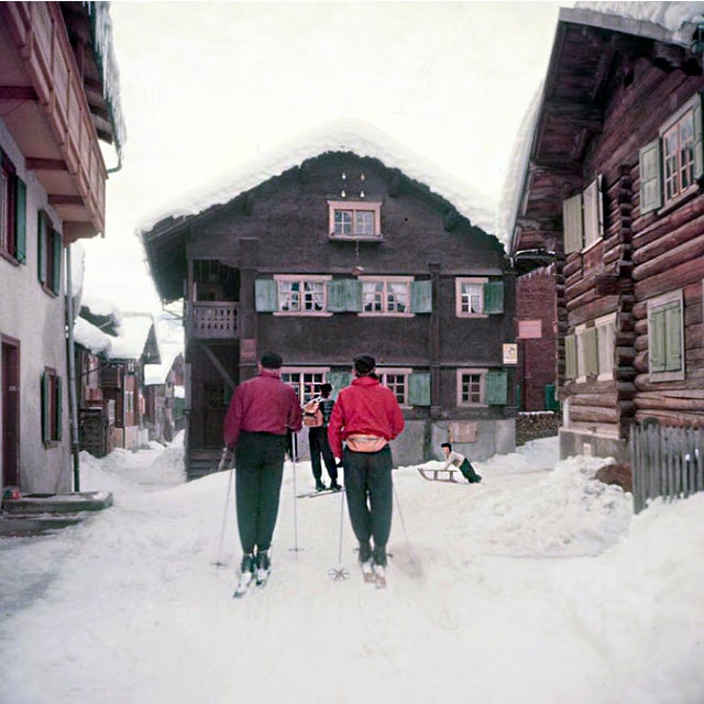 Setting Out by Toni Frissell Two skiers set out through snow covered streets, Klosters, Switzerland, 1951. (Photo by Toni...