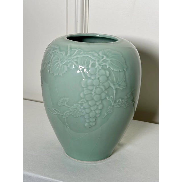 This large celadon green colored vase is gently embossed with round grapes. leaves and curled vine creating a nice tone-...