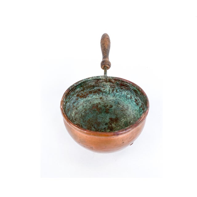 A small antique African copper brazier-style saucepan pot on three short peg legs, possibly used for warming or as a small...