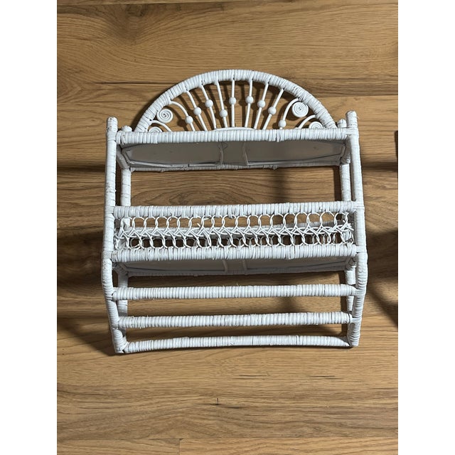 Vintage white wicker painted wall shelves units with a hanger for towels.