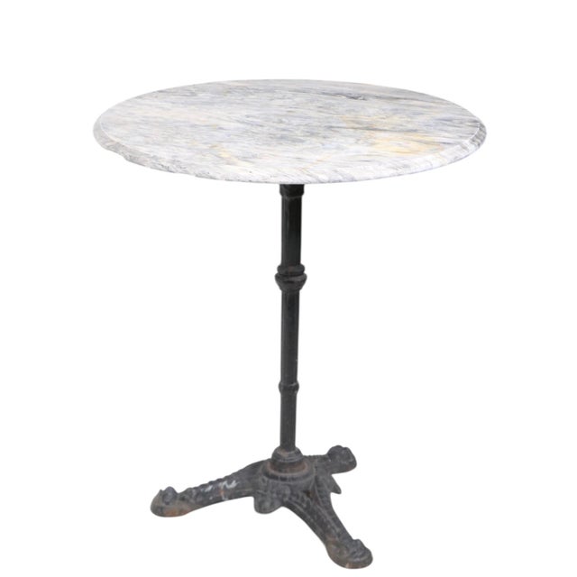 Charming French style antique cafe, bistro, dining table having an ornate cast iron base which supports a round marble...
