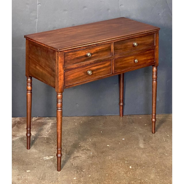 A fine English console or hall table of mahogany from the Georgian era, featuring a moulded top over a frieze of what...