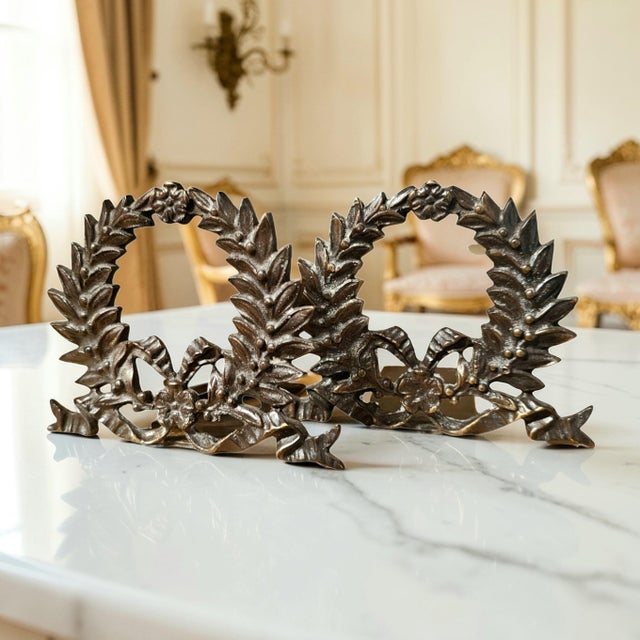 This sculptural pair of cast bronze bookends features a classical laurel garland motif rooted in Greco-Roman symbolism and...