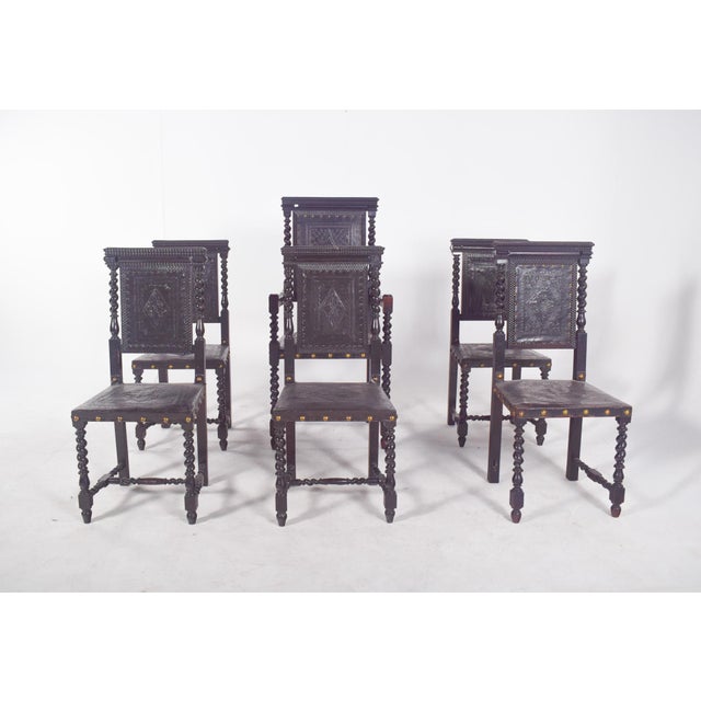 Six dining chairs with leather and nailwork. 20th century Portuguese, in turned wood, carved and patinated in black. The...