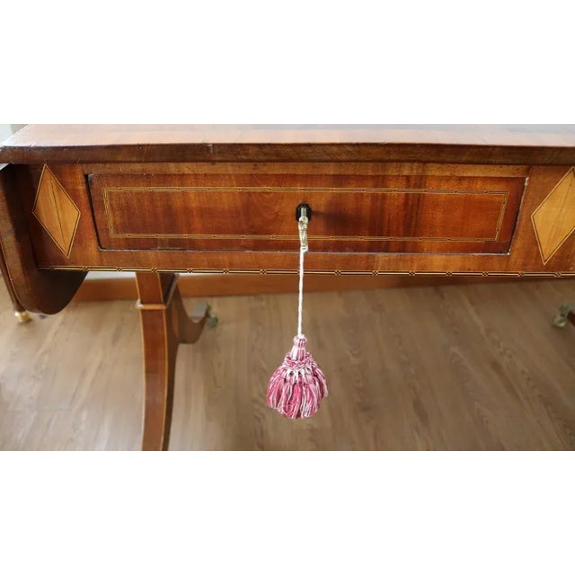 Elegant inlaid mahogany sofa table on Paris saber legs, inlaid and restored with a high French glaze. Top with two side...