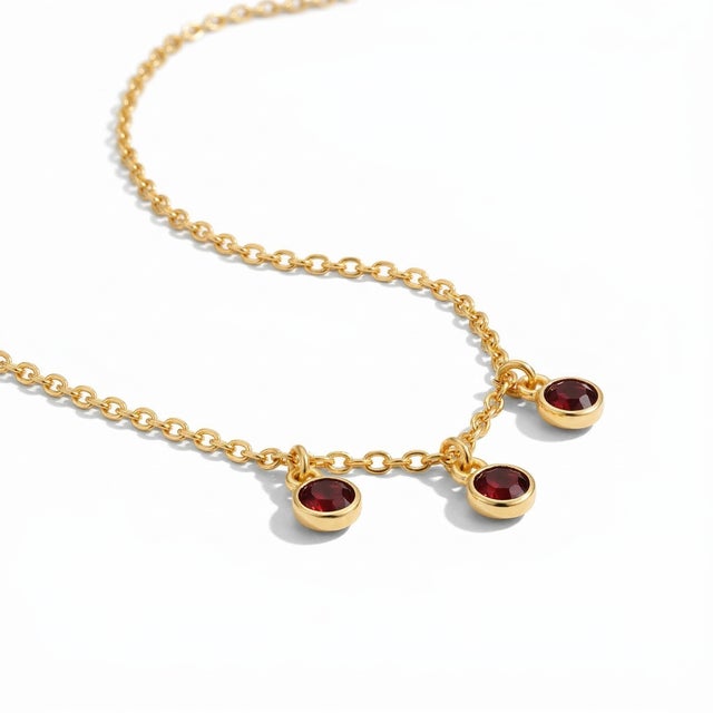 This elegant necklace features the deep, captivating beauty of garnet gemstones, arranged in a delicate three-station drop...