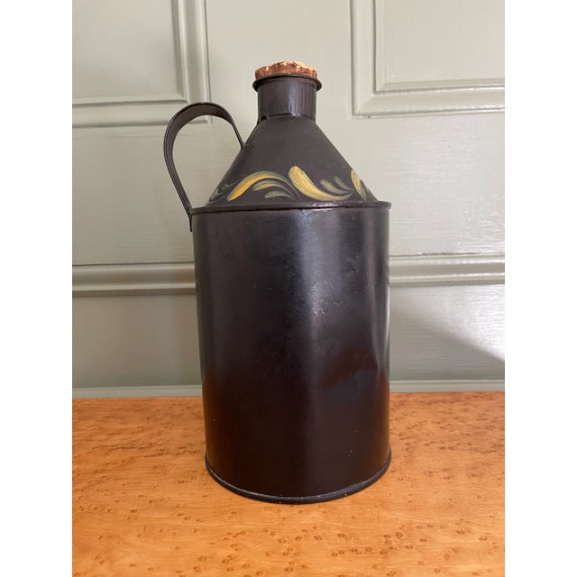 Hand painted tole jug in vibrant hues of red, orange green and yellow, against a black background.