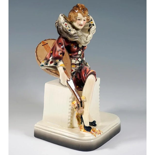 Rare art ceramic figure of the 1920s: depiction of a young musician dressed as pierrette, sitting on a pedestal with her...